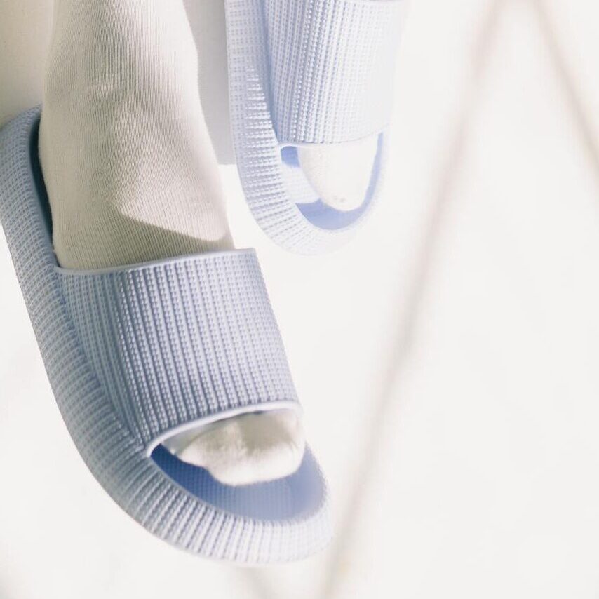 Man wearing socks with sandals and pink shorts, enjoying a sunny day indoors.